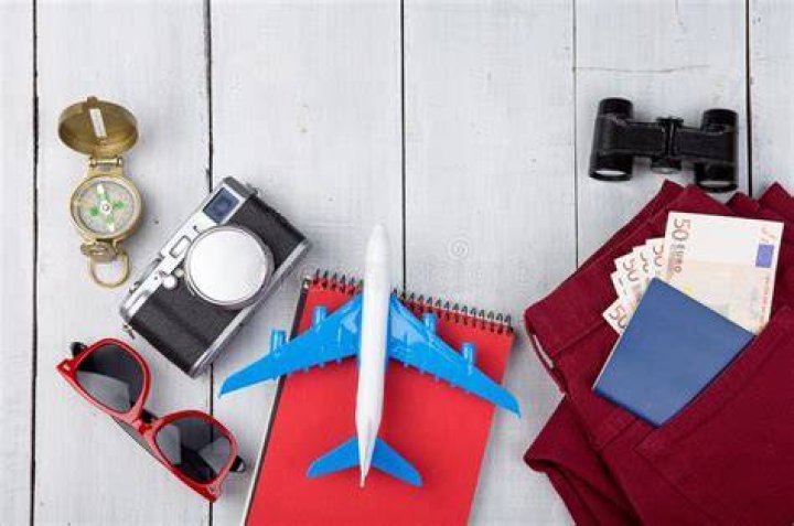 binoculars, sunglasses, compass, and notepad on a desk