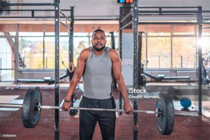 black male muscular athlete practicing deadlift with barbell