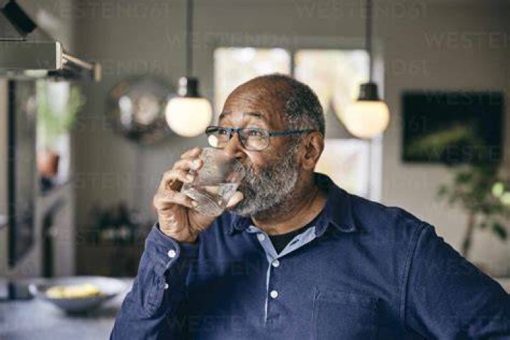 Contemplative senior man drinking water at home contemplative senior man drinking water at home