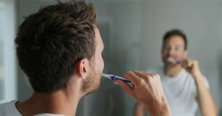 Retired senior man washing toothbrush in bathroom sink at home guy brushing his teeth men's health