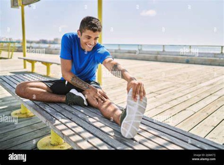 Hispanic runner stretching leg on road near mountain hispanic runner stretching leg on road near mountain