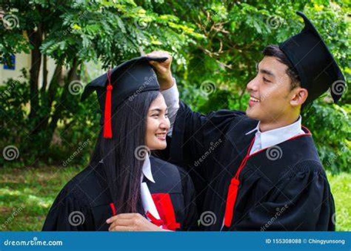 man and woman in graduation robes smiling and hugging
