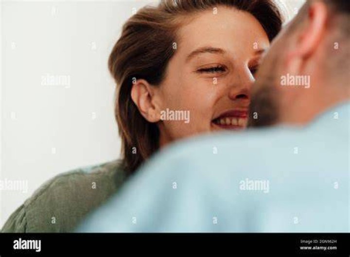 Man And Woman Laughing While Using Mobile Phone While Standing Against Turquoise Wall man and woman laughing while using mobile phone while standing against turquoise wall