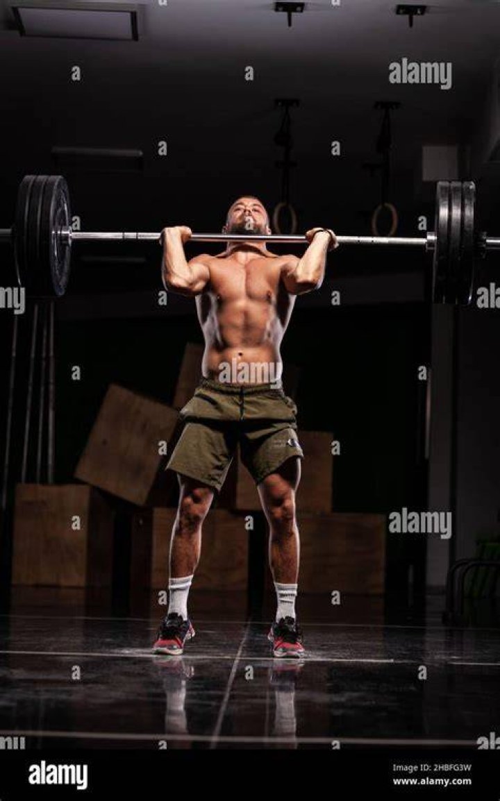 muscular athlete lifting very heavy barbell