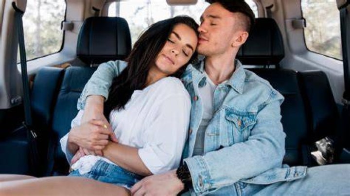 Young couple embracing in back seat of car, side view, night sexo en coche