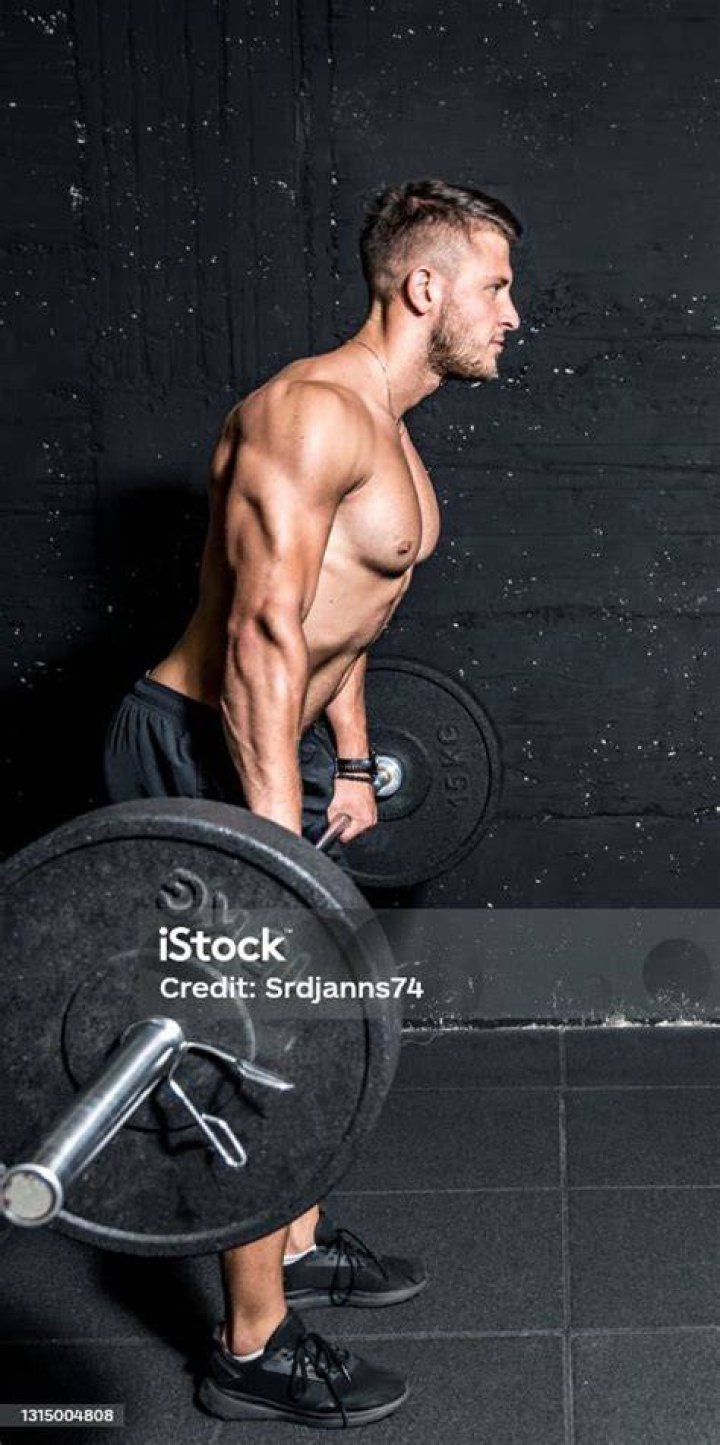 young active strong fit muscular sweaty man with big muscles doing barbell weight lifting cross training workout in the gym dark image real people