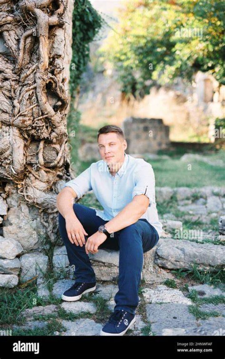 Young man sits on a wall overlooking a town.